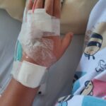 A child's hand with an IV line and bandages, symbolizing healthcare and patient care in a hospital setting.