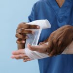 A healthcare professional wrapping a patient's hand with gauze for injury care.